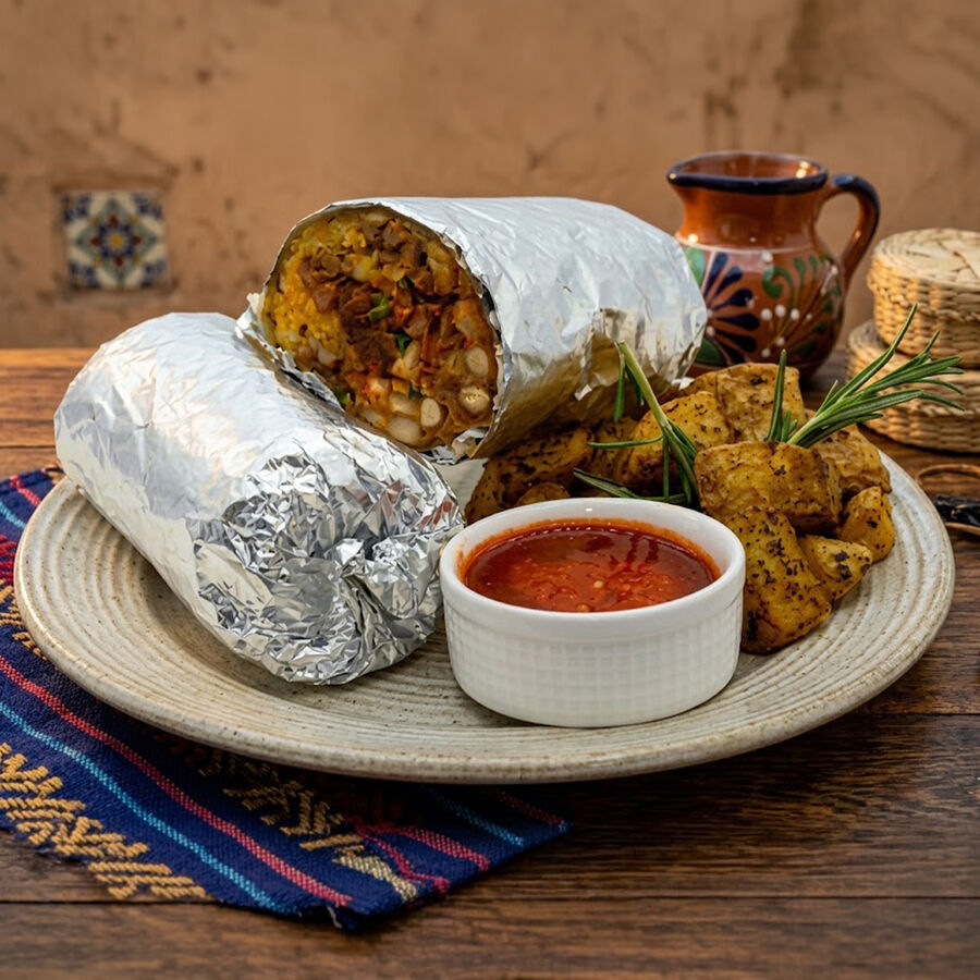 Burrito El Más Cabrón servido con papas y salsa